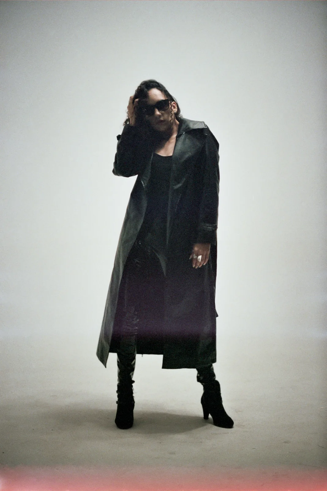 Model wearing a long black coat in a studio
